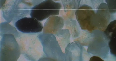 Old-school VHS recording of sand under microscope. Floating bacteria near rocks Vídeos de archivo 199341883