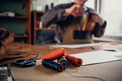 Old school workshop of an exclusive shoemaker. Spools of thread on the workbench Foto stock