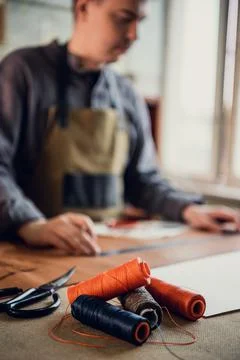 Old school workshop of an exclusive shoemaker. Spools of thread on the workbench Stock Photos