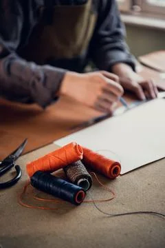 Old school workshop of an exclusive shoemaker. Spools of thread on the workbench Stock Photos
