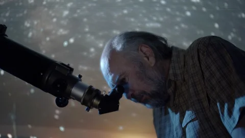 Old scientist man using astronomer telescope with stars on the sky swirling t Video stock 107360704
