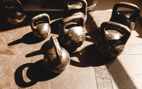 Old scratch dumbbells on a rubber surface in gym in sunlight Stock Photos