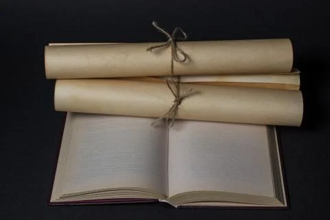 Old scrolls lie on an open book. Education concept. Ancient knowledge. on the bo Stock Photos