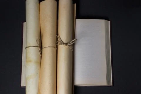Old scrolls lie on an open book. Education concept. Ancient knowledge. on the bo Stock Photos