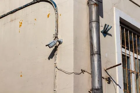 Old security camera mounted on a weathered concrete wall of an urban building Stock Photos