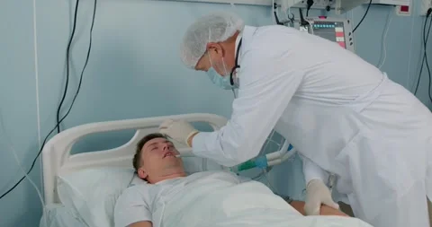 Old senior doctor checking pupillary response of week young sick patient Stock Footage 268691095