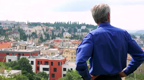 Old senior man looks at the city - shot on back - city (buildings) in background Stock Footage