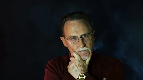 Old senior man man in glasses looking at camera on dark background. Stock Footage 129178299