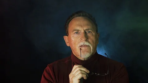 Old senior man man in glasses looking at camera on dark background. Stock Footage 129181213