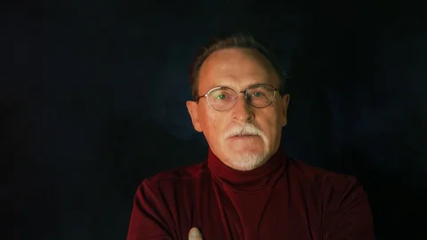 Old senior man man in glasses looking at camera on dark background. Stock Footage 129181404