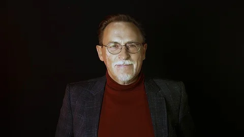 Old senior man man in glasses looking at camera on dark background. Stock Footage 129187285