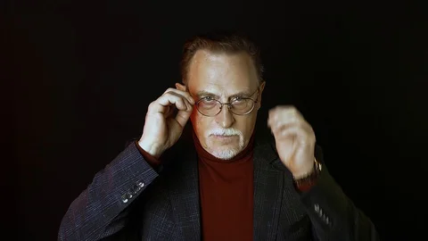 Old senior man man in glasses looking at camera on dark background. Stock Footage 129188255