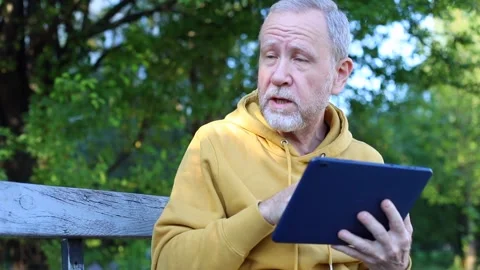 Old senior man using tablet talking with little grandson enjoying sunny day outs Vidéo 142318924