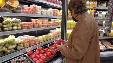 Old senior woman picking using a black N95 face mask and jacket picking peppers Stock Footage 150448587