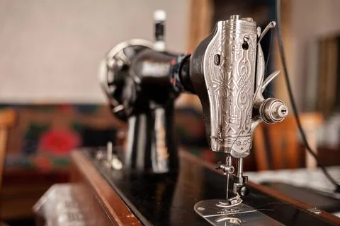 Old sewing machine stands on the table at home ready to work and sew. Stock Photos