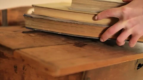 Old shabby books stack.Hands stack worn books on a wooden table Stock Footage 260448502