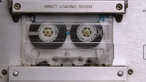 An old shabby compact audio cassette spins in a tape recorder. Detailed macro Stock Footage 145754376