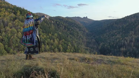 An old shaman performs a magic ritual with the help of a bell standing on the Stock Footage 119445233