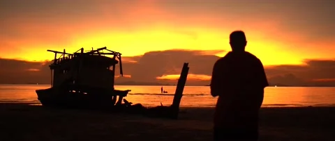 An old ship and the figure of a man at sunset by the sea Stock Footage 174047929