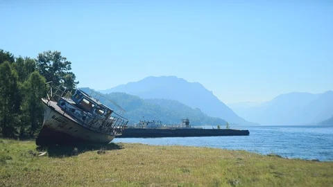 Old ship waiting for repairs lying on the shore of a mountain lake Stock Footage 105946359