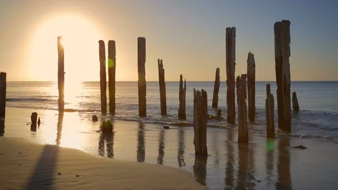 Old shipwreck remains as small waves splash into shore at sunset Stock Footage 126615017
