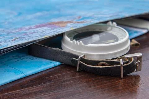 Old simple compass with a leather strap and a map. Compass as a navigator Stock Photos