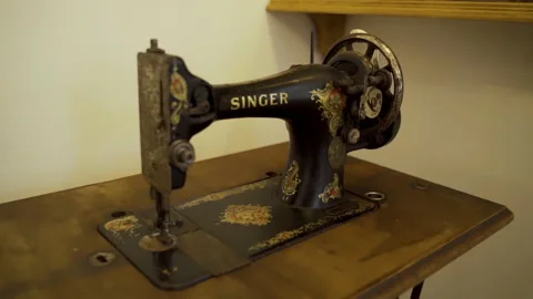 An old Singer sewing machine standing on a table against the wall. Video stock 231738496