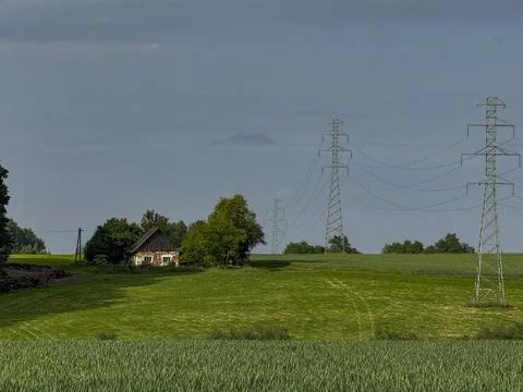 An old, single house in the fields with a power line running through it. Stock Photos