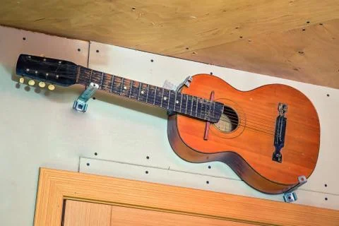 Old six string guitar hangs on the wall. Over door. Stock Photos