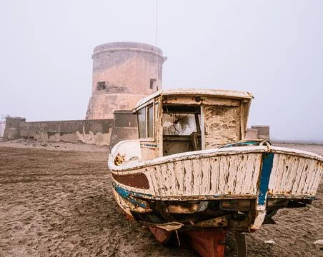 Old small abandoned ship with a tower in the background Stock Photos