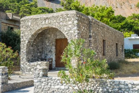 Old small brick cube shape house with wooden door. The house in the Greece co Stock Photos