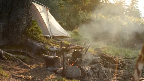 Old small kettle is heated on a bright bonfire on a green mountain meadow Video stock 95681346