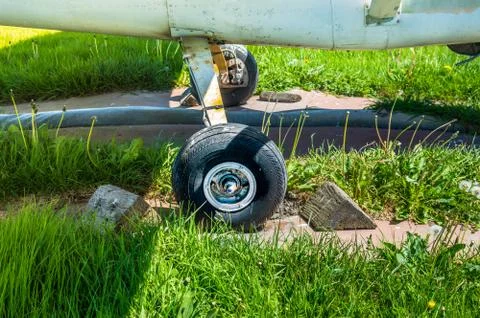 Old small single engine airplane wheel and wooden chocks on parking pad. Stock Photos