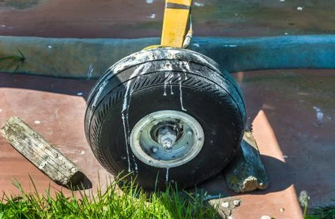 Old small single engine airplane wheel and wooden chocks on parking pad. Stock Photos