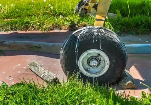 Old small single engine airplane wheel and wooden chocks on parking pad. Stock Photos