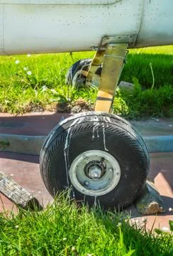 Old small single engine airplane wheel and wooden chocks on parking pad. Stock Photos