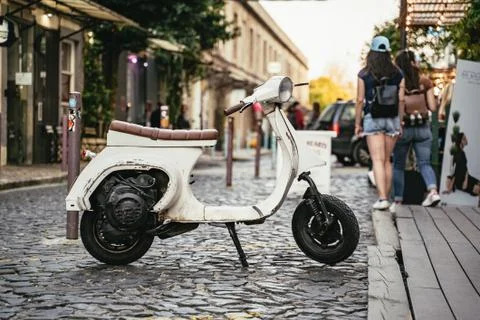 Old small white scooter parked in a cobbled street Stock Photos
