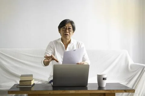 Old smart lady using laptop for e-learning at living room, Foto stock