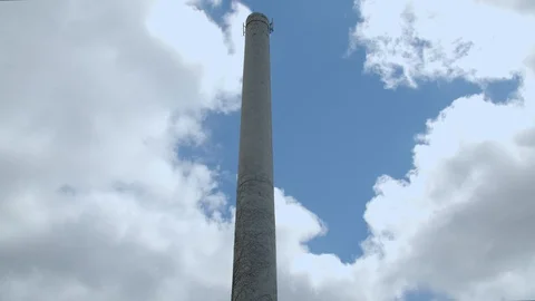 Old smoke stack rises to the blue sky with clouds. 4k60p Stock Footage 130146824