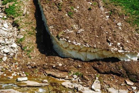 Old snow from the winter with soil on the surface while hiking in the summer Stock Photos