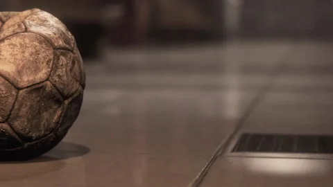Old soccer ball resting on a floor near a drain during indoor playtime Video stock 344966204