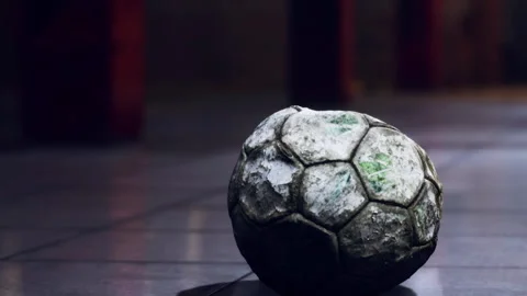 Old soccer ball rests on floor in empty room during evening light Stock Footage 344969483