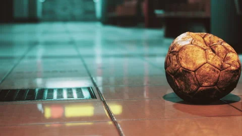 Old soccer ball sits on the floor in an empty hallway near a grating Stock Footage 344969669