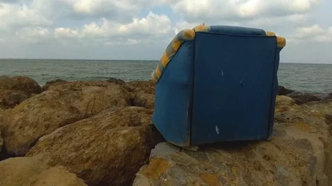 Old sofa on the rocks by the sea Stock Footage 127884947