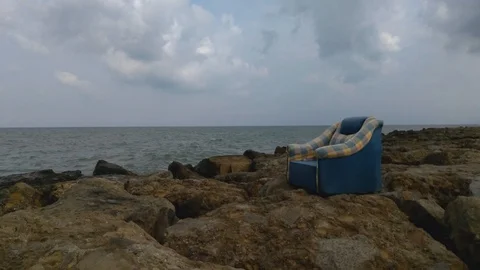 Old sofa on the rocks by the sea Stock Footage 127885294