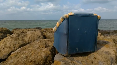 Old sofa on the rocks by the sea Stock Footage 127926831