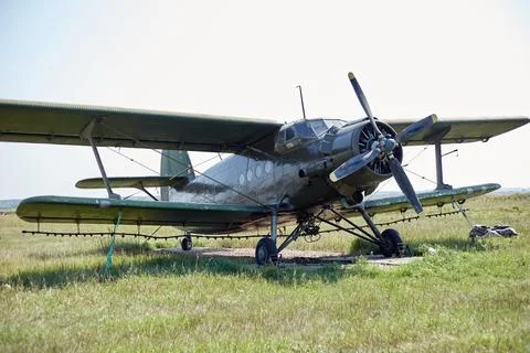 An old Soviet AN 2 aircraft stands in a field on a green meadow Stock Photos
