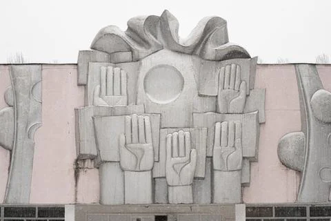 An old Soviet metal panel at the school, which shows the raised hands Stock Photos