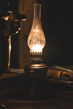 An old Soviet rifle lies on a table next to a kerosene lamp in the semi-dar.. Stock Photos