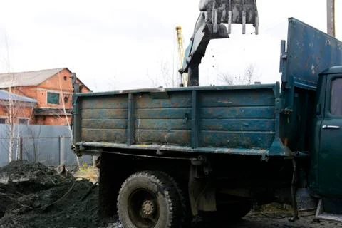 An old Soviet tractor digs and loads waste stone processing near the shop Stock Photos